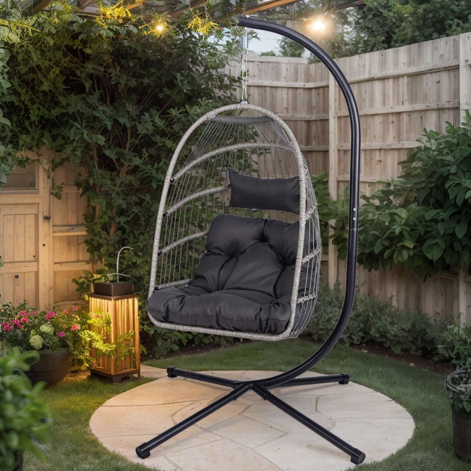 Outdoor egg hanging chair with stand in a garden setting, featuring a modern design and plush cushions.