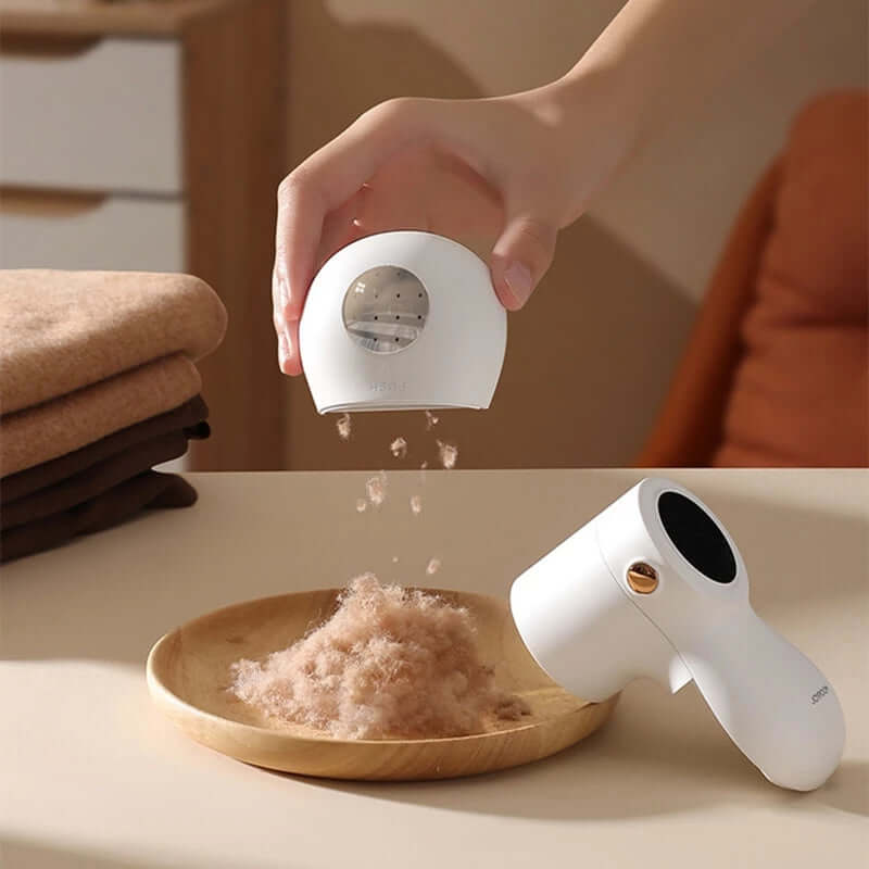 Electric lint remover with LED display removing lint from fabric into a wooden bowl.