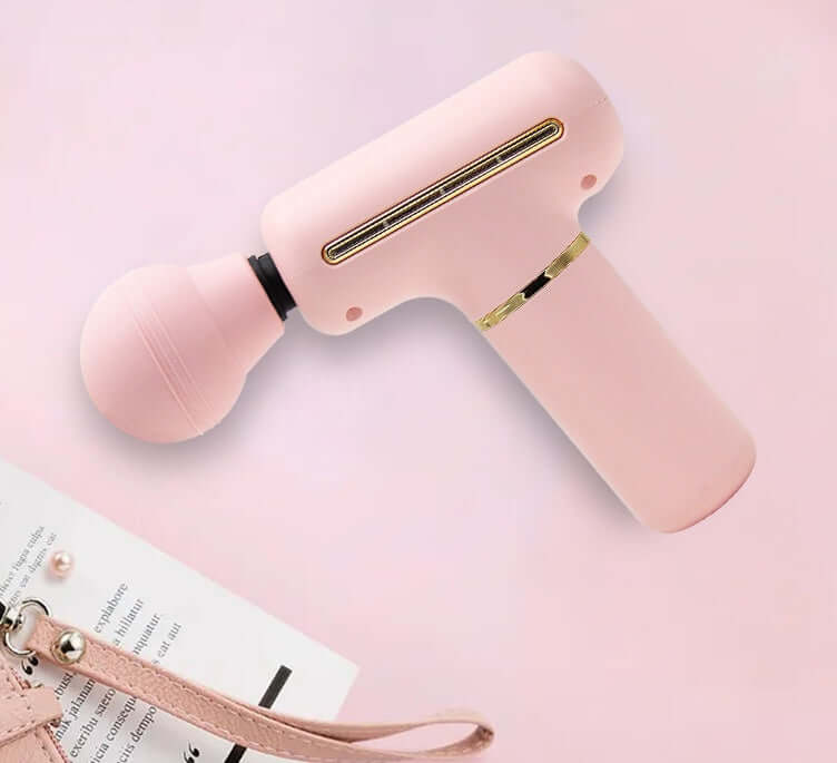 Portable muscle massage gun in pink color with a round massage head on a pastel background.